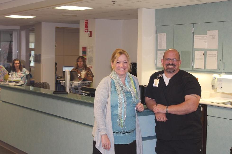 man in scrubs standing next to woman in hospital